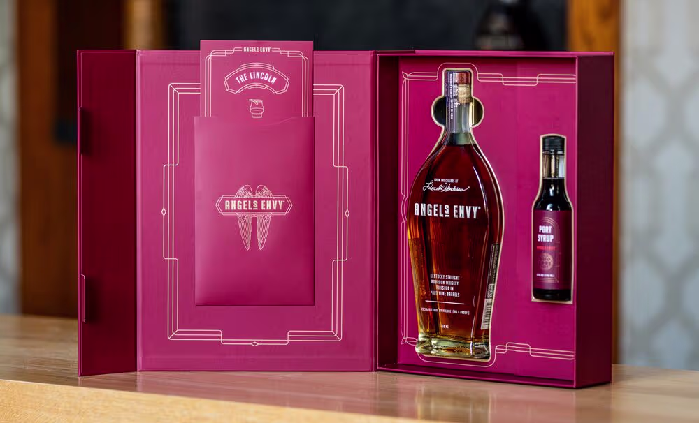 The Lincoln Cocktail Kit with a ruby presentation box, a bottle of Angel’s Envy bourbon, and a bottle of Angel’s Envy Port Syrup.