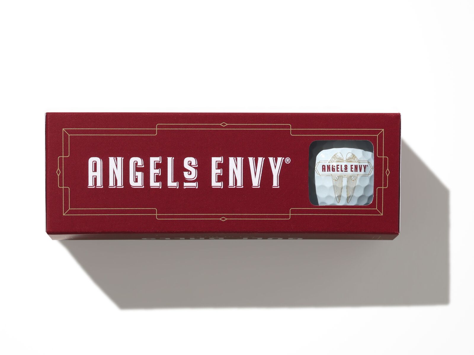 The ruby Angel’s Envy Golf Ball Set in a ruby branded box featuring a white ball showcasing the logo.