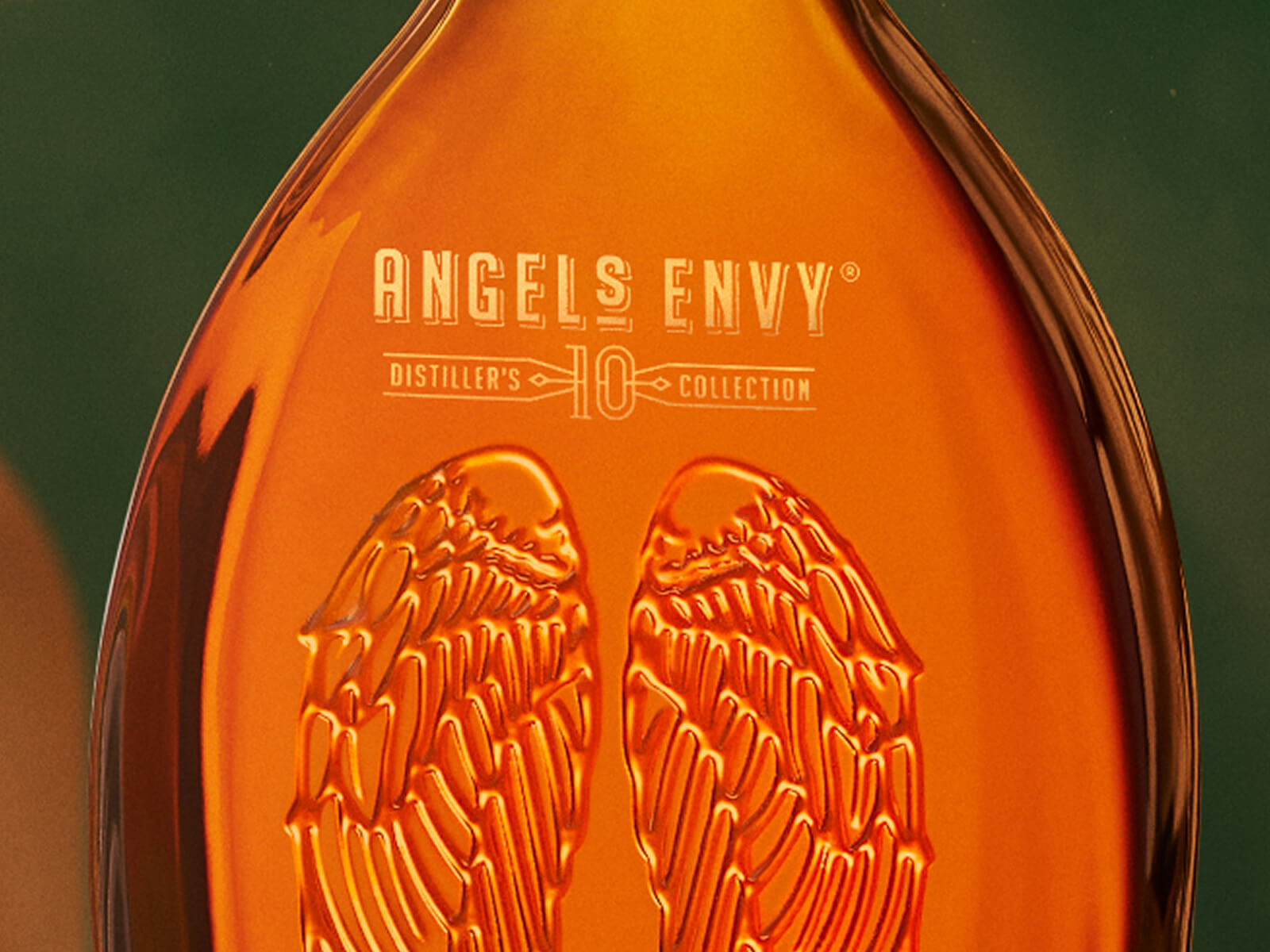 Close-up of Angel’s Envy bottle showcasing the brand’s signature wings and the number 10, teasing the upcoming Spring 2026 Cask Strength release.