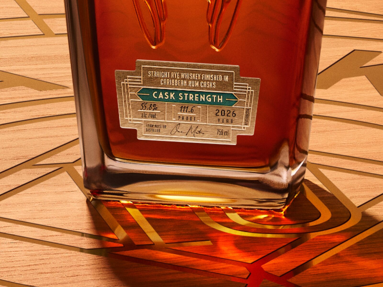 A close-up of the Angel’s Envy 10 Cask Strength Rye bottle featuring the gold product label, presented on a logo-engraved table in the Cask Archives room.