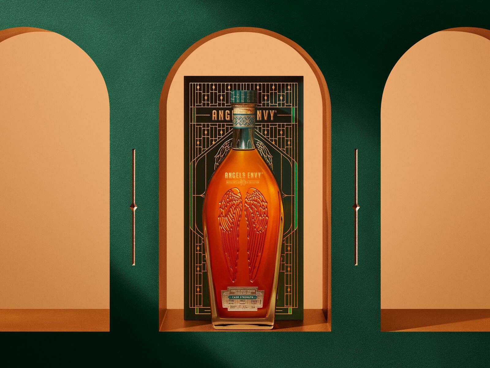 Angel’s Envy 10 Cask Strength Rye bottle displayed in front of the limited-edition presentation box, framed by golden arched niches and set in the Cask Archives room.