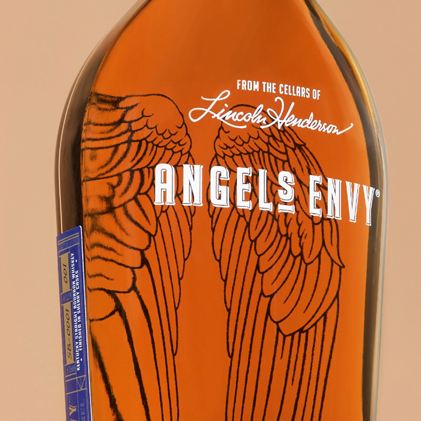 A close-up angle of the Angel’s Envy Single Barrel Bourbon Finished in Oloroso Sherry Wine Barrels bottle with a soft orange background.