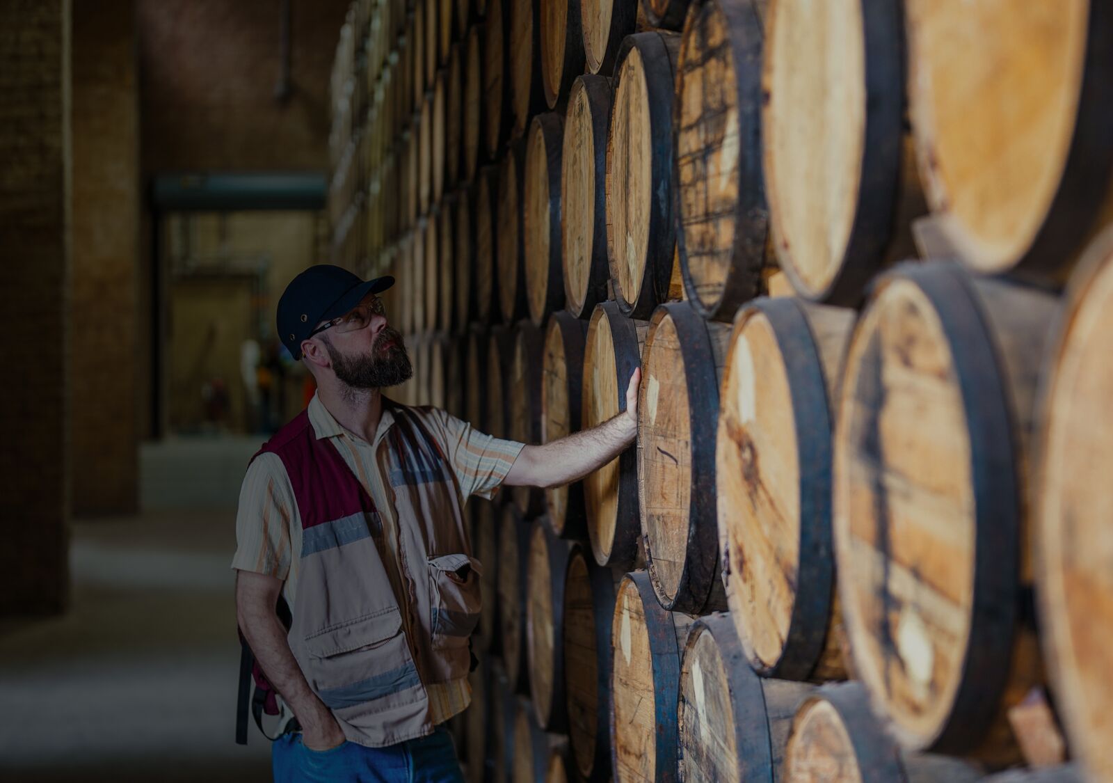 Master Distiller Owen Martin in the Angel’s Envy rickhouse, touching and observing a stacked column of barrels.