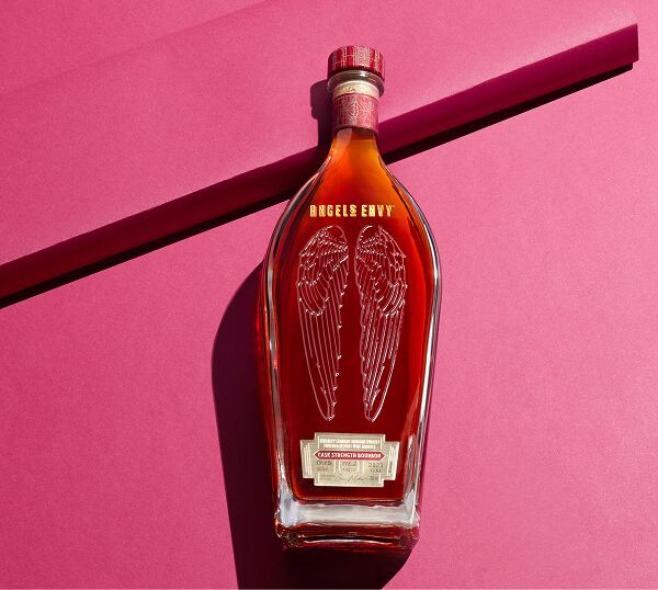 A bottle of Angel’s Envy Cask Strength Bourbon 12th Edition a brightly lit ruby background.