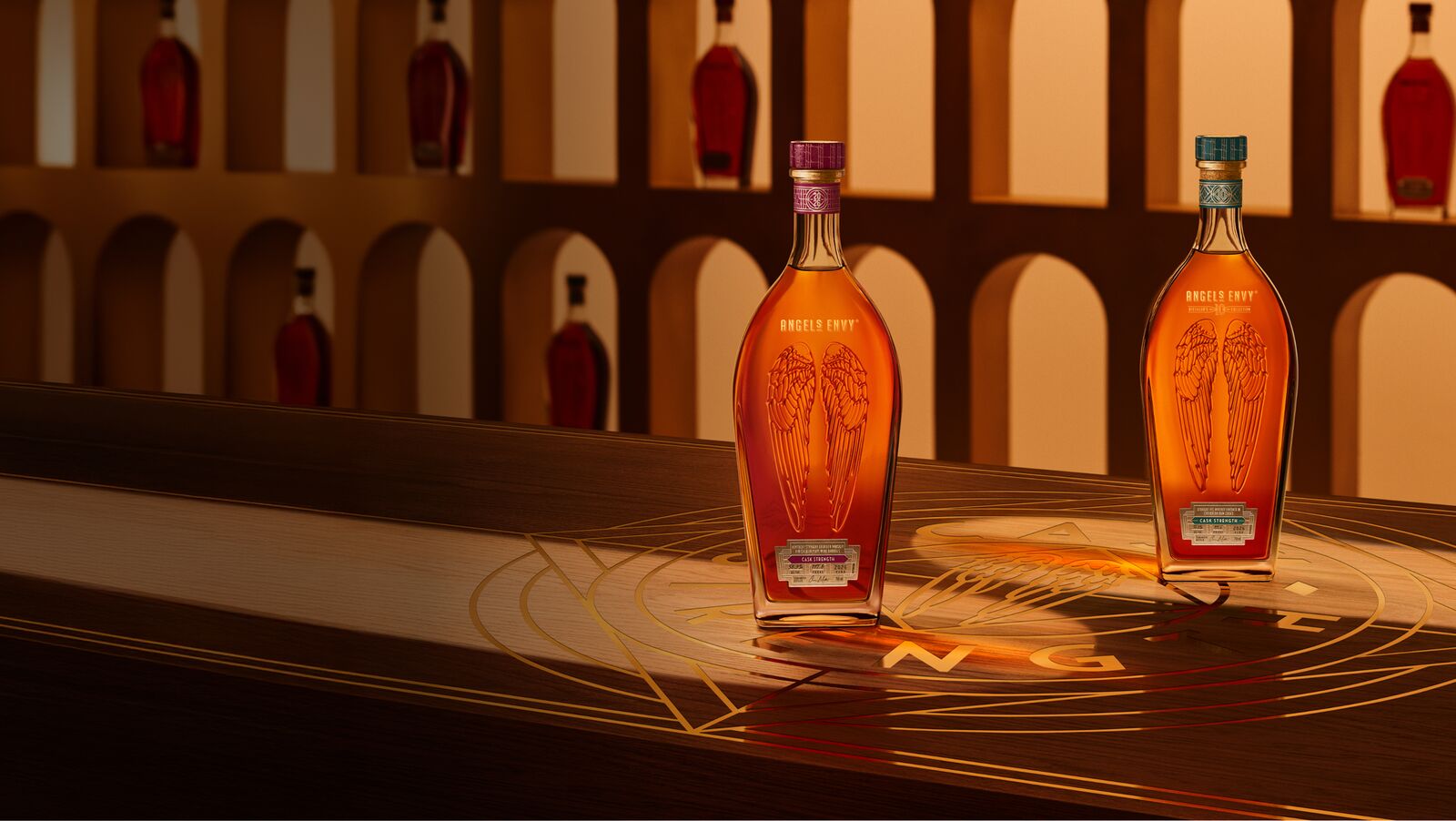 Angel’s Envy 10 Cask Strength Rye and 2026 Cask Strength Bourbon bottles displayed together on a logo-engraved table in the Cask Archives room for the Spring 2026 dual release.