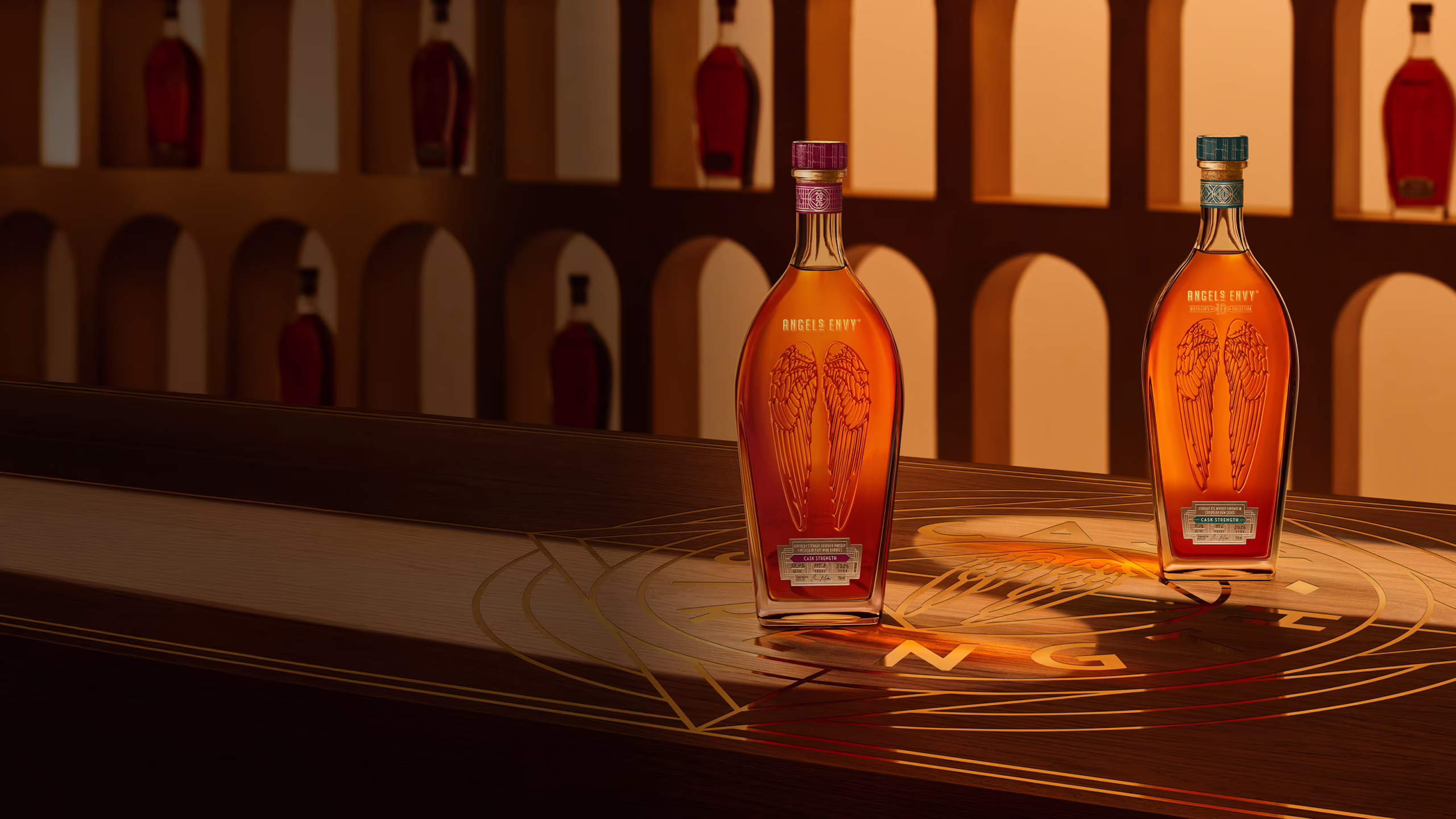 Angel’s Envy 10 Cask Strength Rye and 2026 Cask Strength Bourbon bottles displayed together on a logo-engraved table in the Cask Archives room for the Spring 2026 dual release.