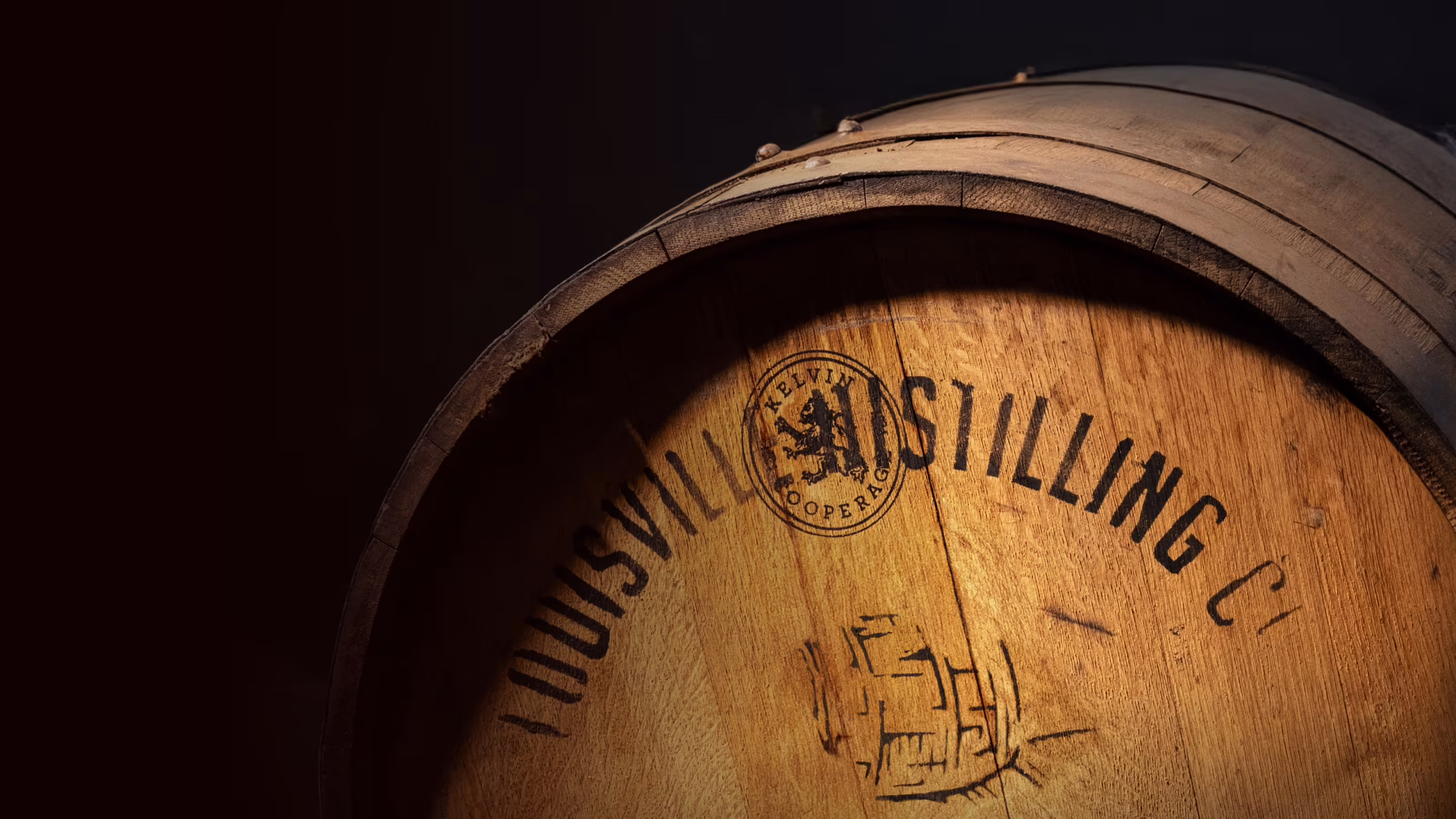 A warmly lit close-up of an Angel’s Envy oak barrel with a cascading shadow.