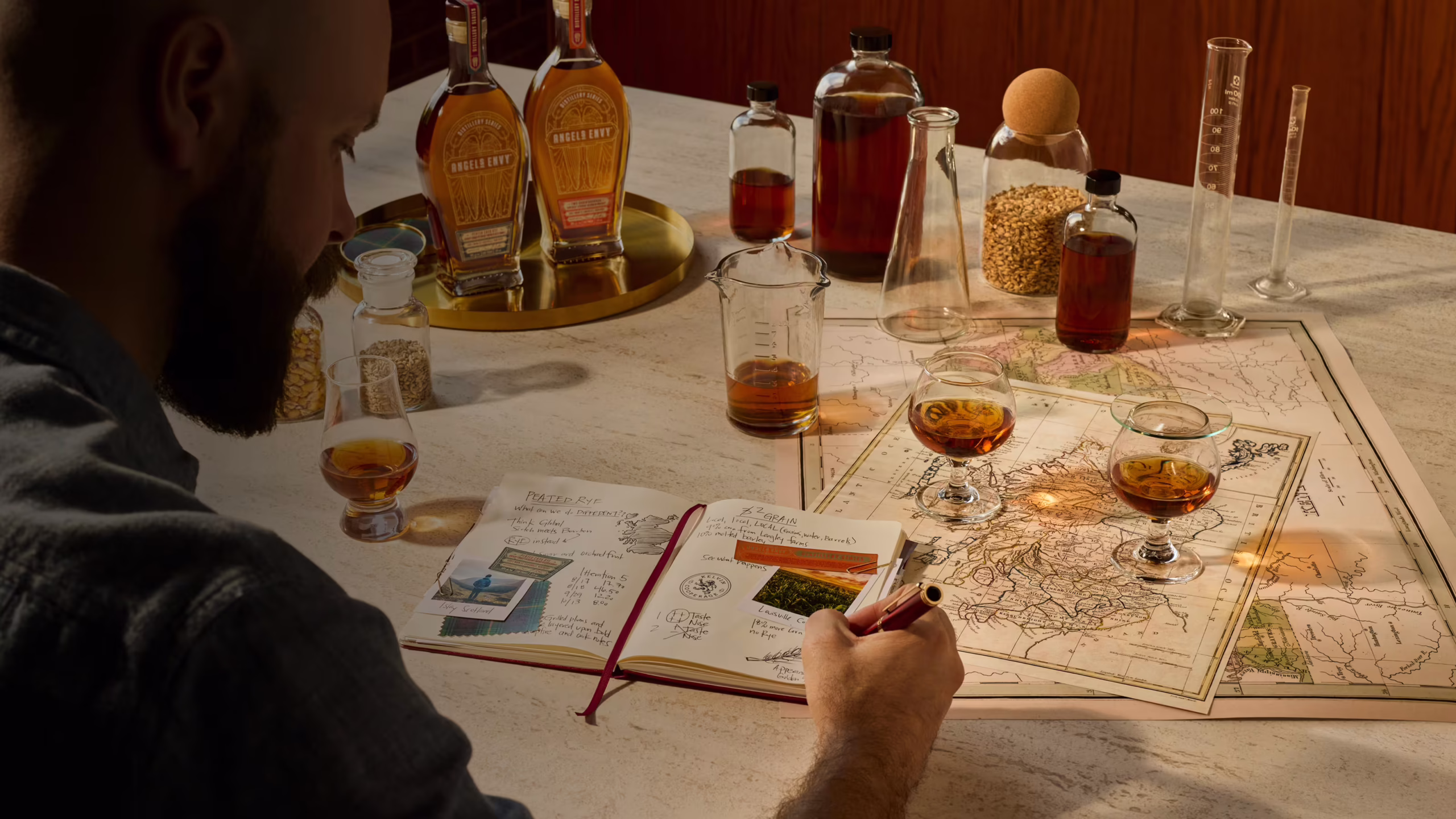 Behind-the-scene shot for the Distillery Series featuring Master Distiller Owen Martin documenting in his journal with a table full of spirits, notes, and tasting glasses.