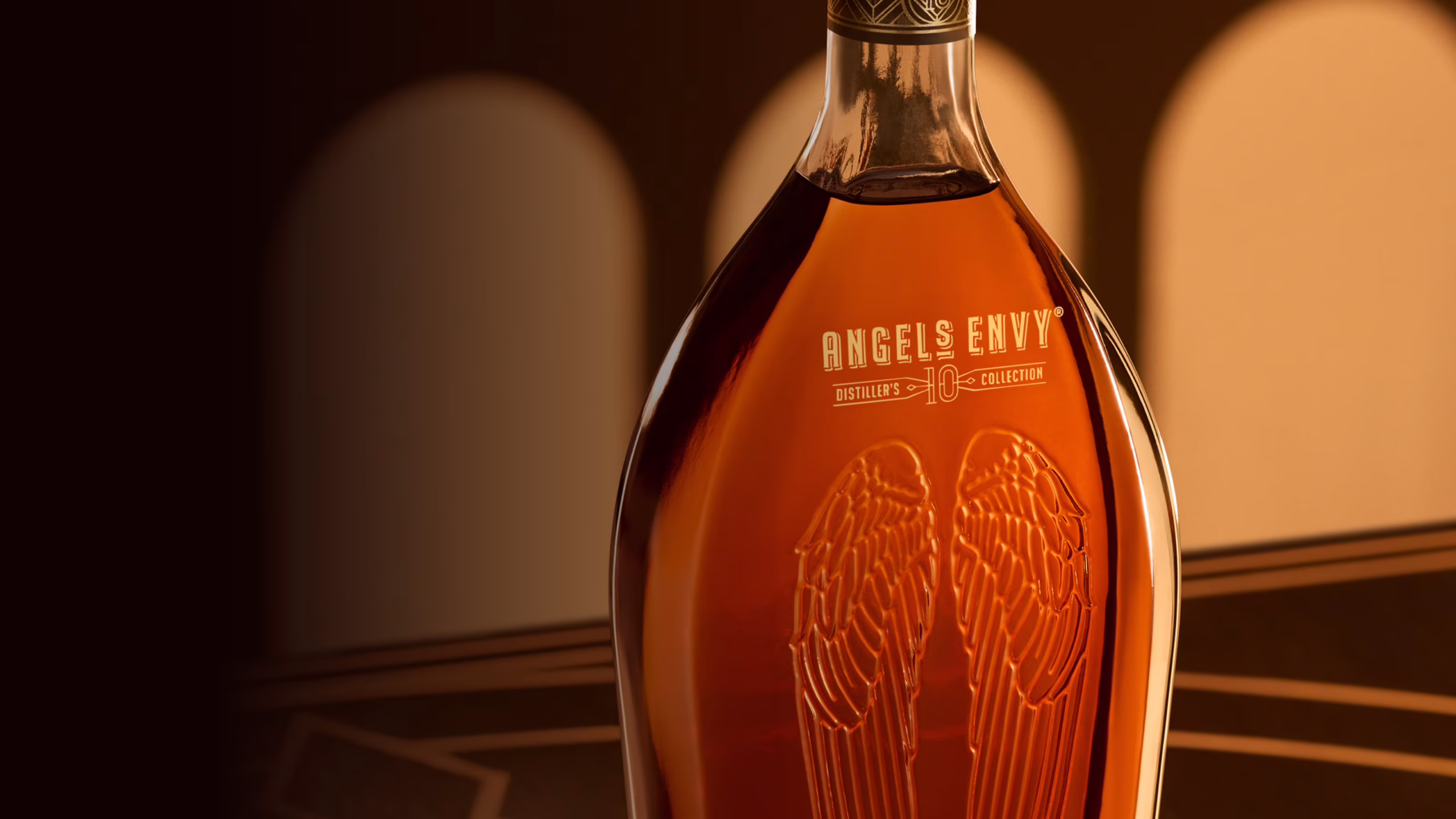 A warmly lit, close-up view of the Angel’s Envy 10 Cask Strength bottle set inside the modern Cask Archives room.