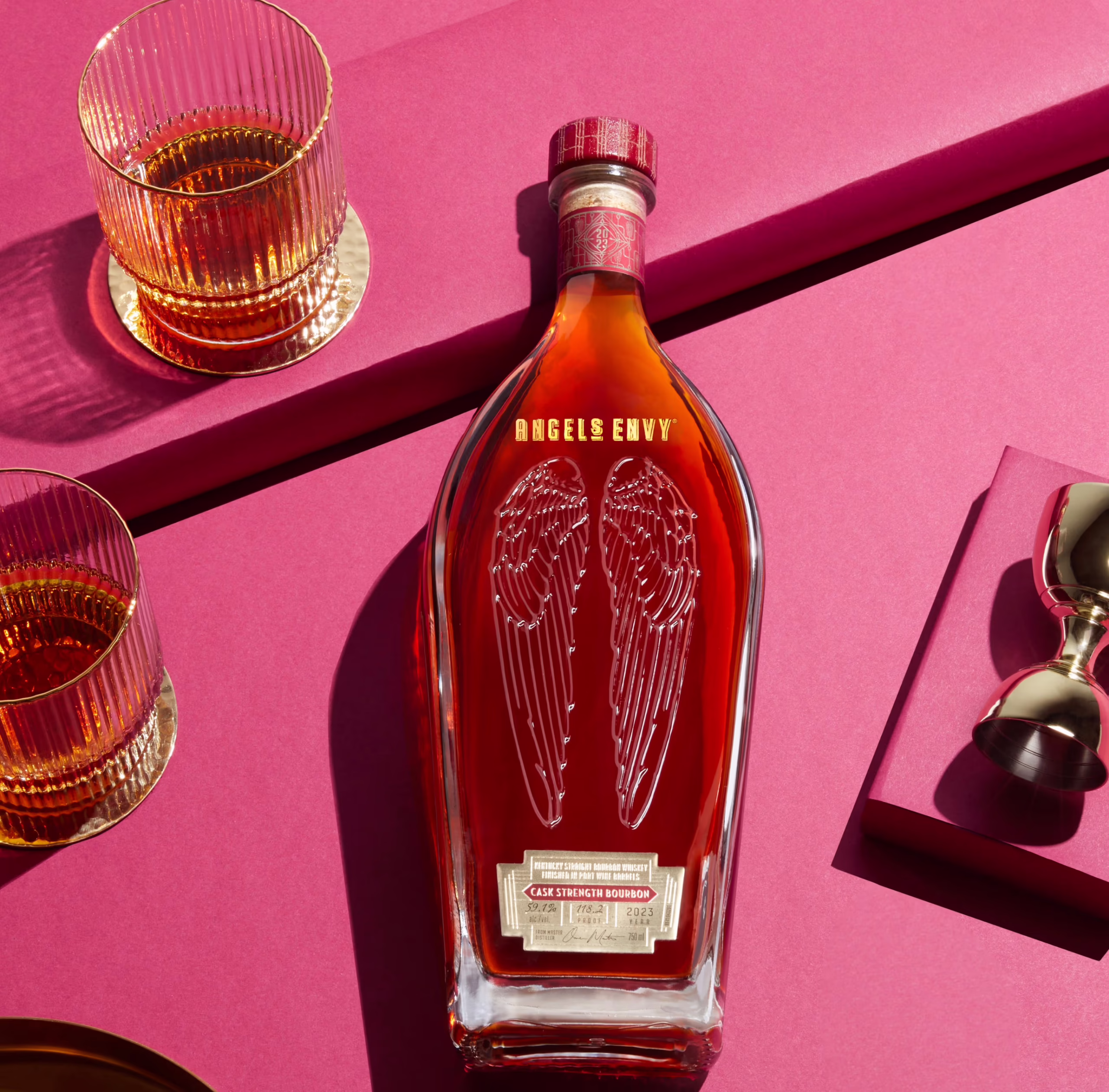 A bottle of Angel’s Envy Cask Strength Bourbon 12th Edition a brightly lit ruby background.
