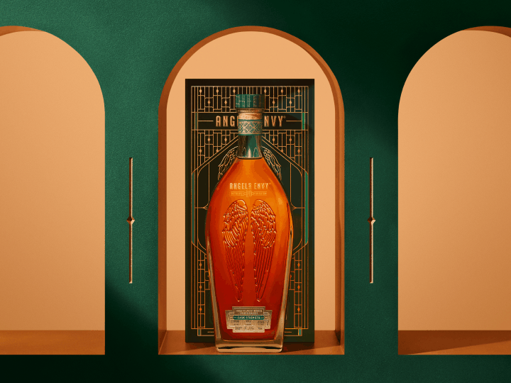 A gif rotation featuring an image of an Angel’s Envy 10 Cask Strength Rye bottle and Angel’s Envy 2026 Cask Strength Bourbon bottle displayed in front of the limited-edition presentation box, framed by an arched niche within the Cask Archives room.