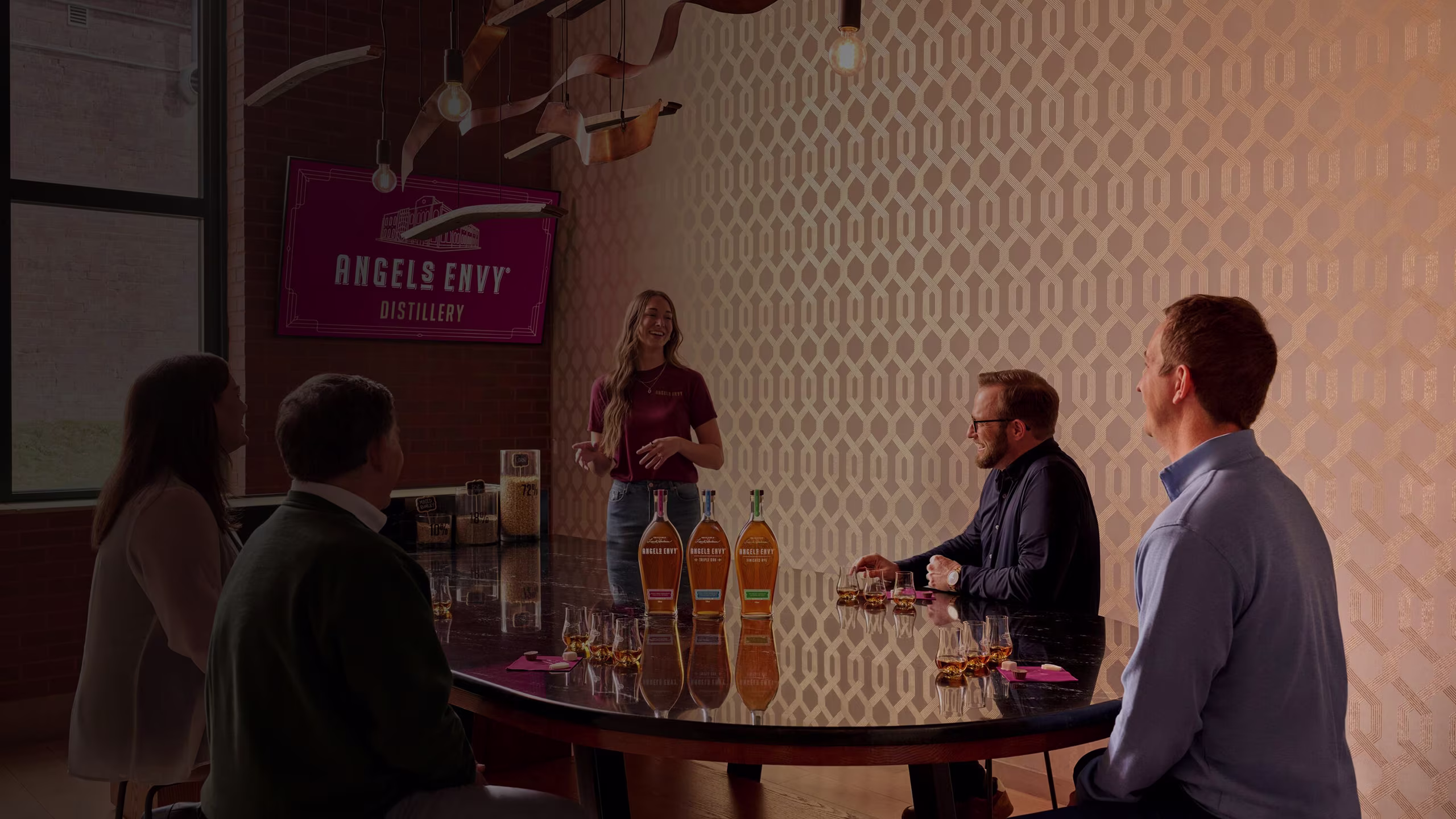 Set inside the Angel’s Envy Distillery in Louisville, Kentucky, a group of people sit attentively around a table and listen to a guide tasting experience.