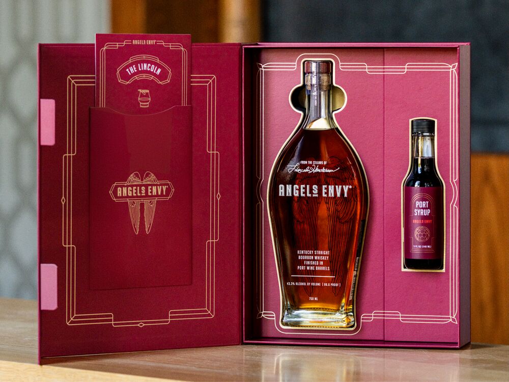 The Lincoln Cocktail Kit with a ruby presentation box, a bottle of Angel’s Envy bourbon, and a bottle of Angel’s Envy Port Syrup.