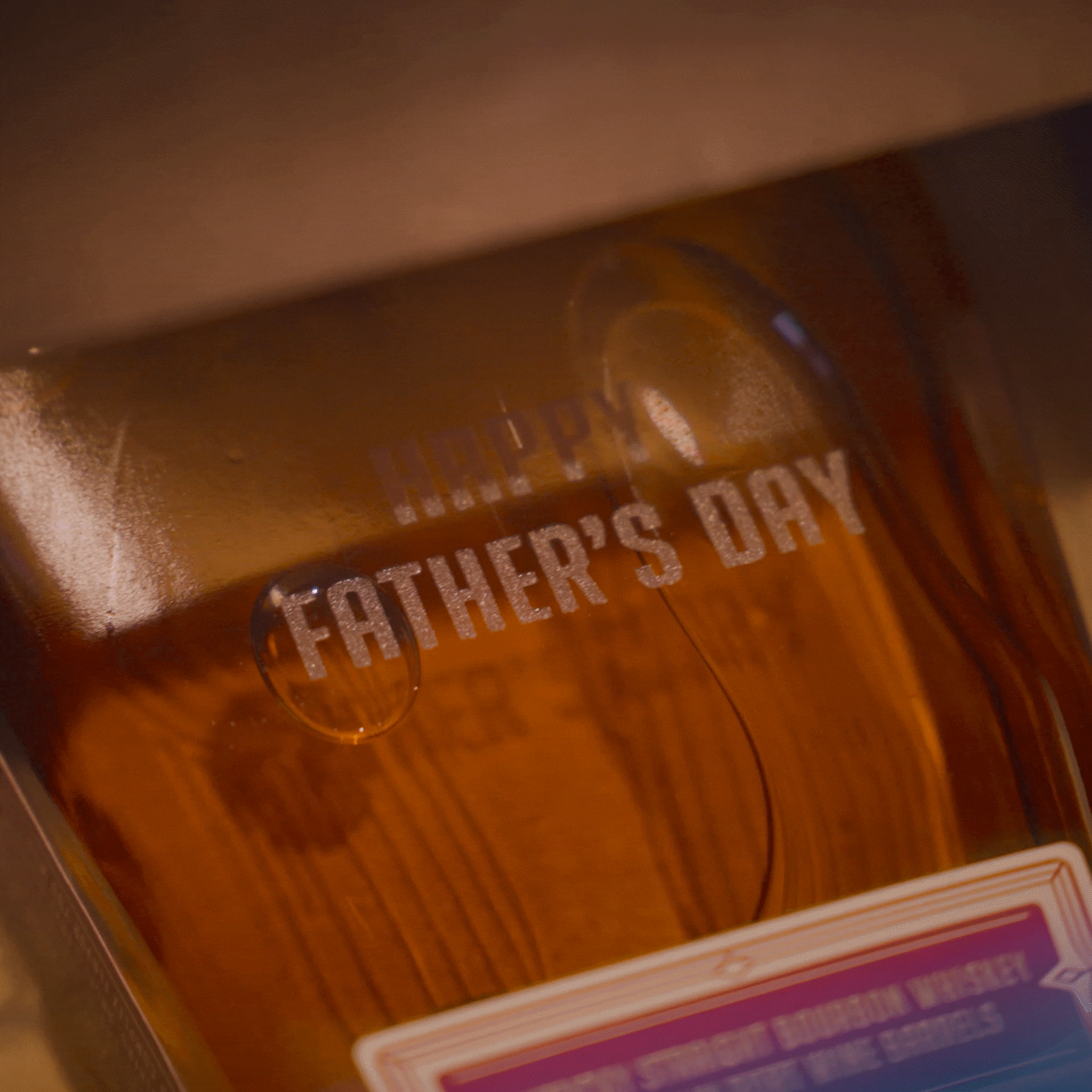 An Angel’s Envy bottle half-way through the process of being laser-etched with a custom “Happy Father’s Day” message.
