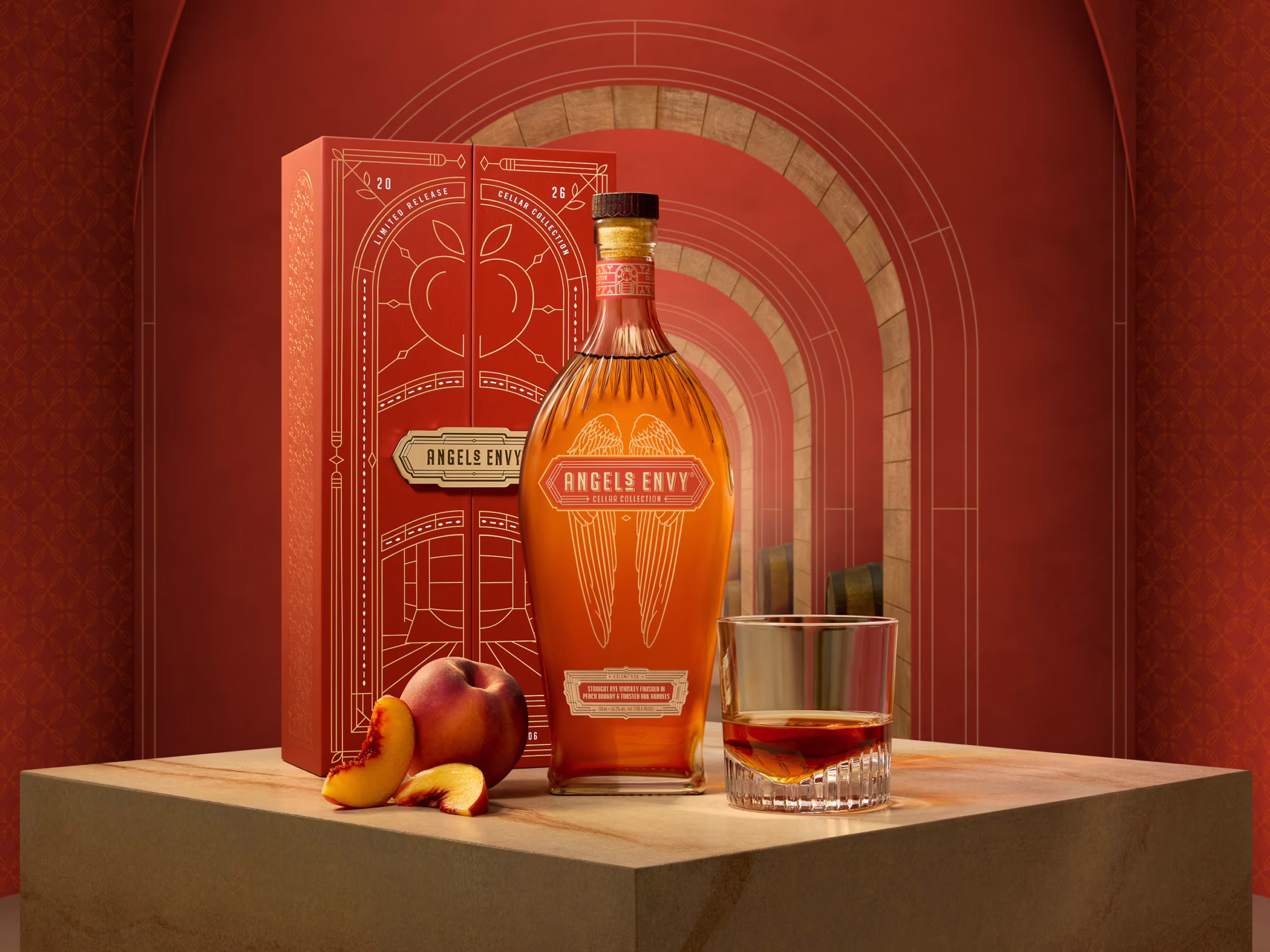A bottle of Cellar Collection Rye sitting in front of a red decorative Angel’s Envy presentation box next to a rocks glass and peaches against a warm red backdrop.