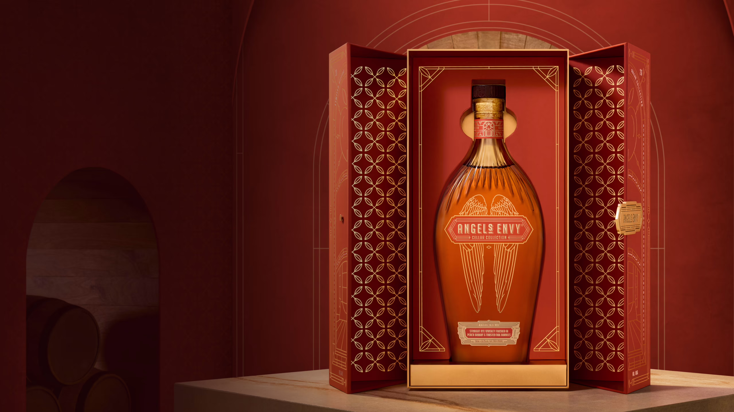 A bottle of Angel’s Envy Cellar Collection Rye displayed inside an opened presentation box with gold geometric detailing.