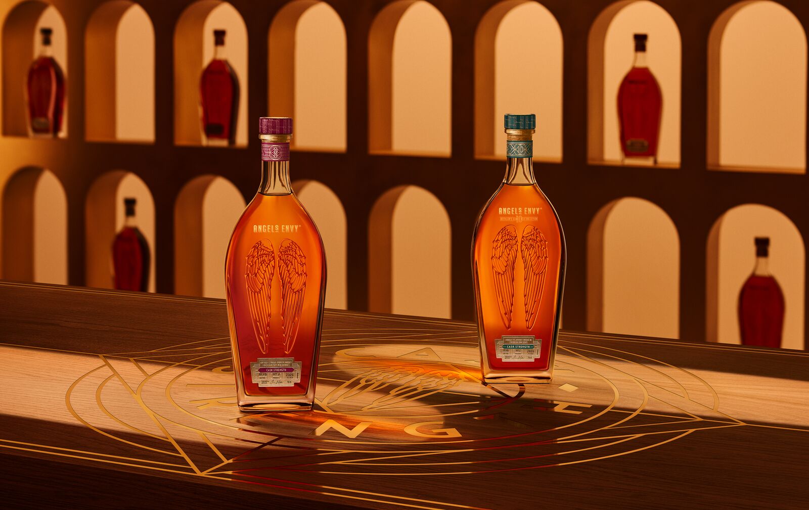 Angel’s Envy 10 Cask Strength Rye and 2026 Cask Strength Bourbon bottles displayed together on a logo-engraved table in the Cask Archives room for the Spring 2026 dual release.